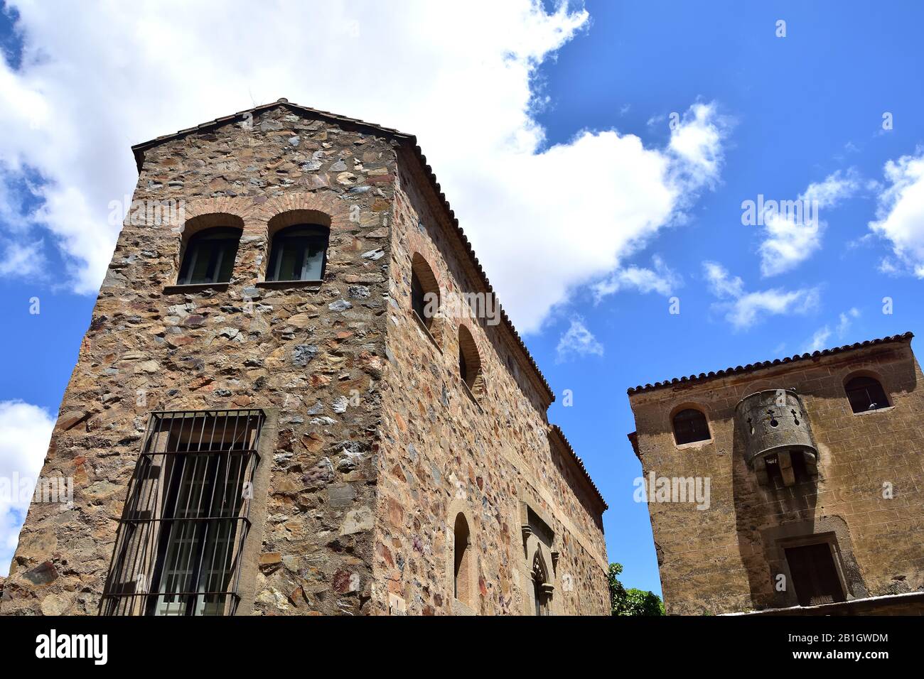 Two historic stone buildings in Caceres seen from below with overhead light that give it a dark look Stock Photo