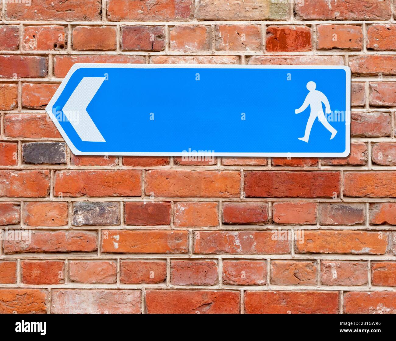 3D computer graphic, direction sign towards a walkway against a red brick wall Stock Photo