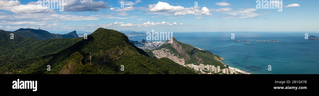 Rio de Janeiro wide panorama with tropical rainforest in the foreground and Corcovado and Two Brothers mountain, shantytown of Rocinha and coast Stock Photo
