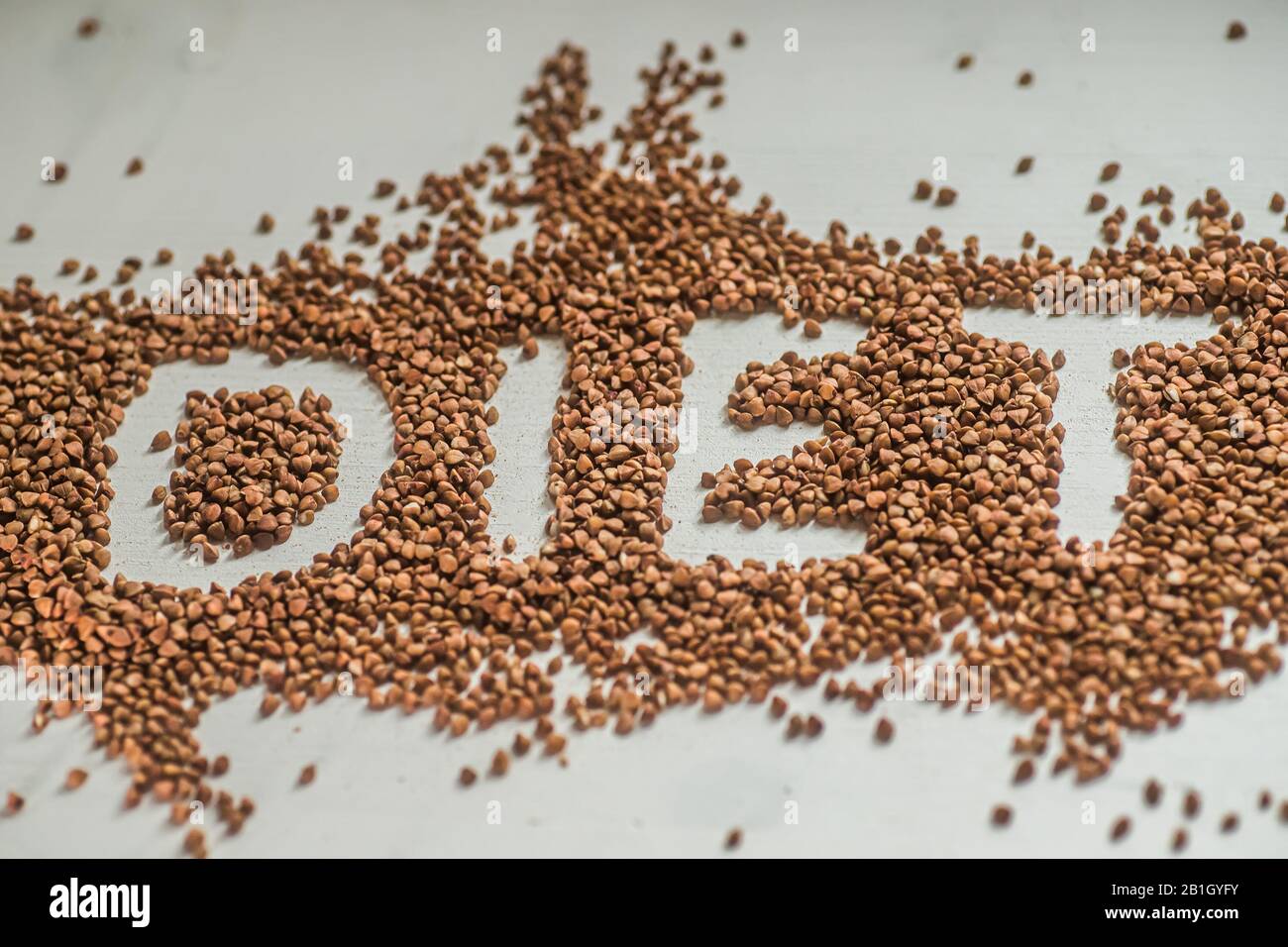 buckwheat diet. Scattered on wooden white background of grit. word
