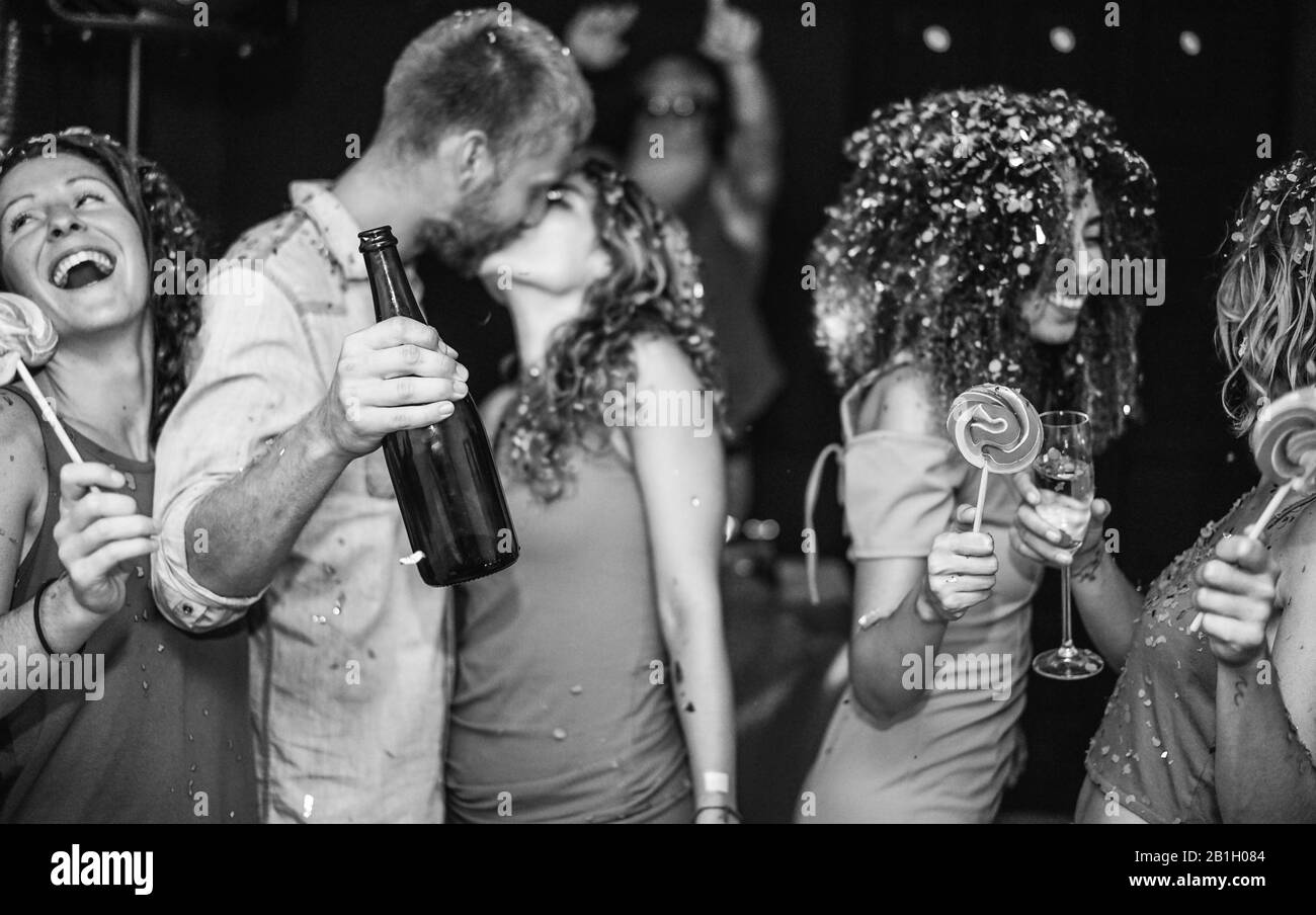 Trendy happy friends dancing at vintage night party with confetti, champagne and candy lollipop - Young people having fun inside nightclub - Youth and Stock Photo