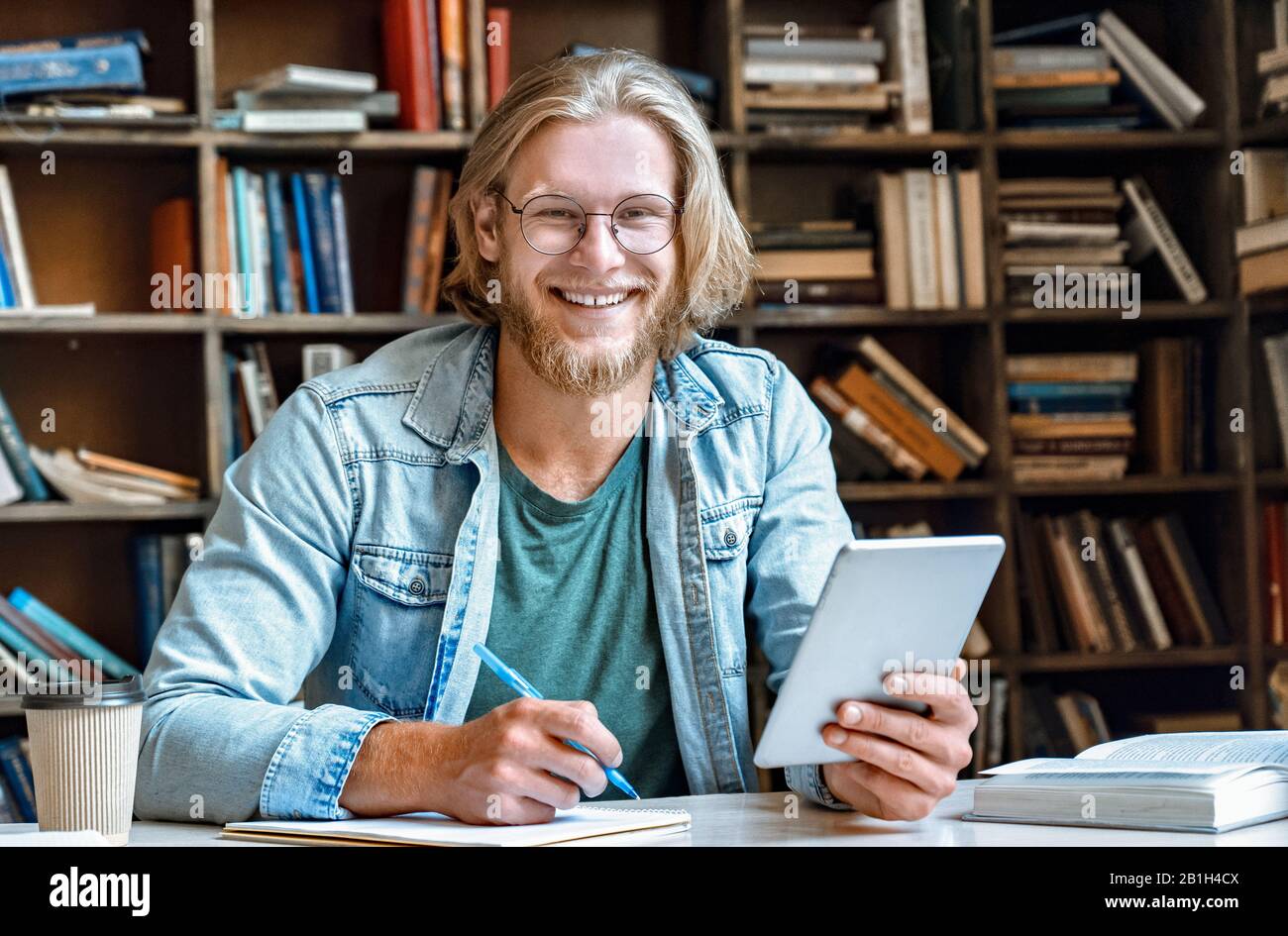 Student hold modern tablet make notes in notebook empty smile at camera Stock Photo