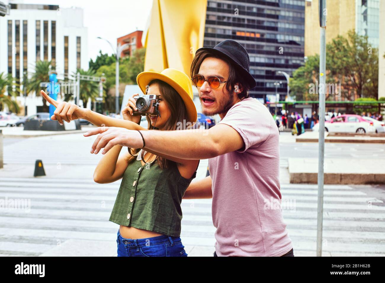 Portrait of young couple traveling and taking photo while pointing at monument on street of Mexico City center Stock Photo