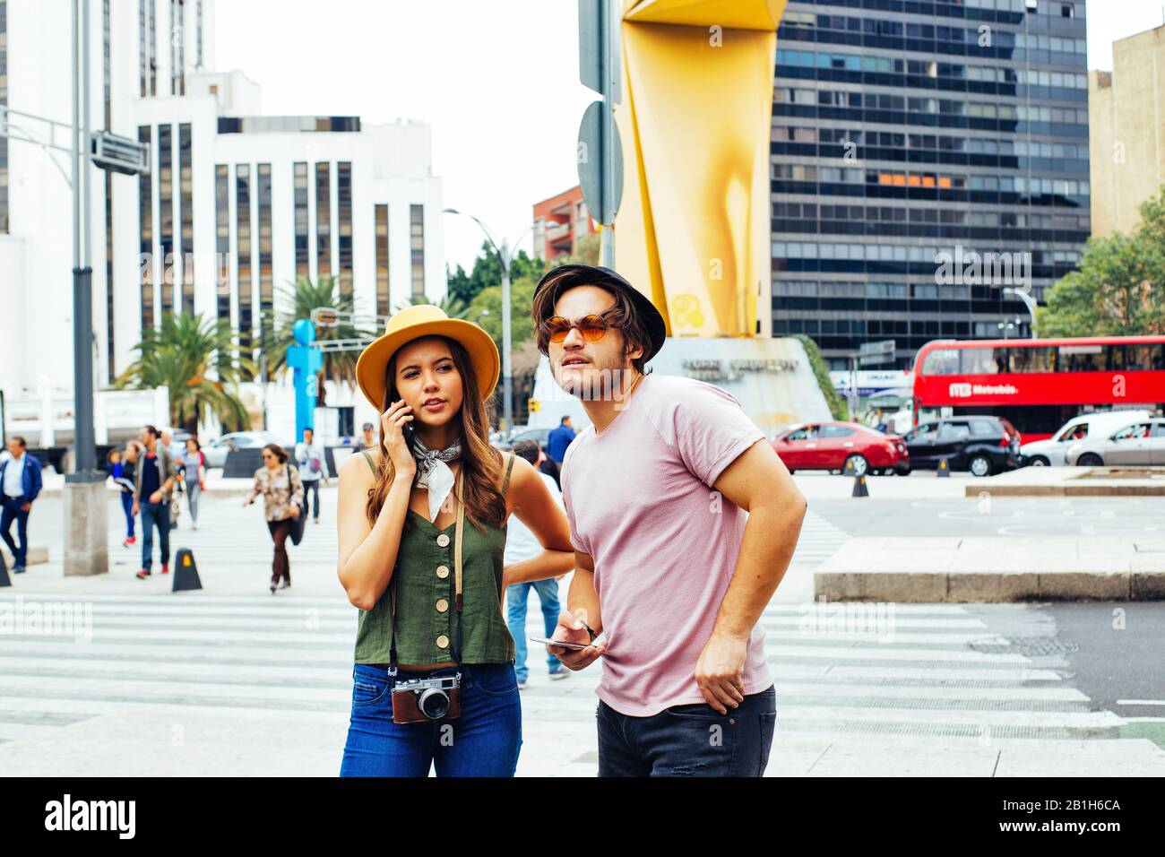 Portrait of young couple of tourists  with camera talking on phone on street of Mexico City center Stock Photo