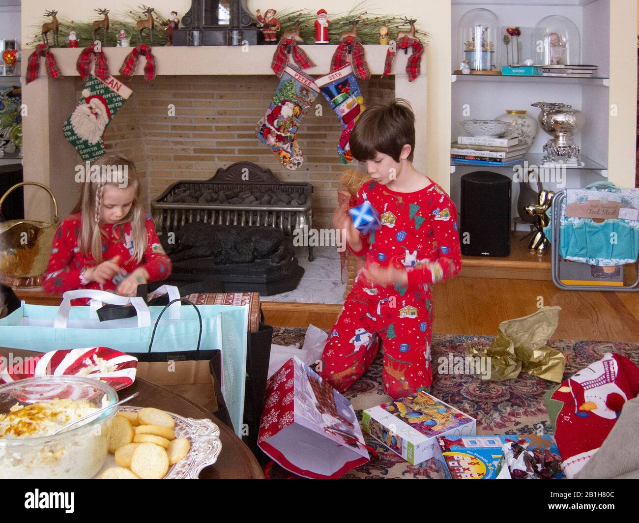 Two children opening gifts from Santa on Christmas morning. Stock Photo