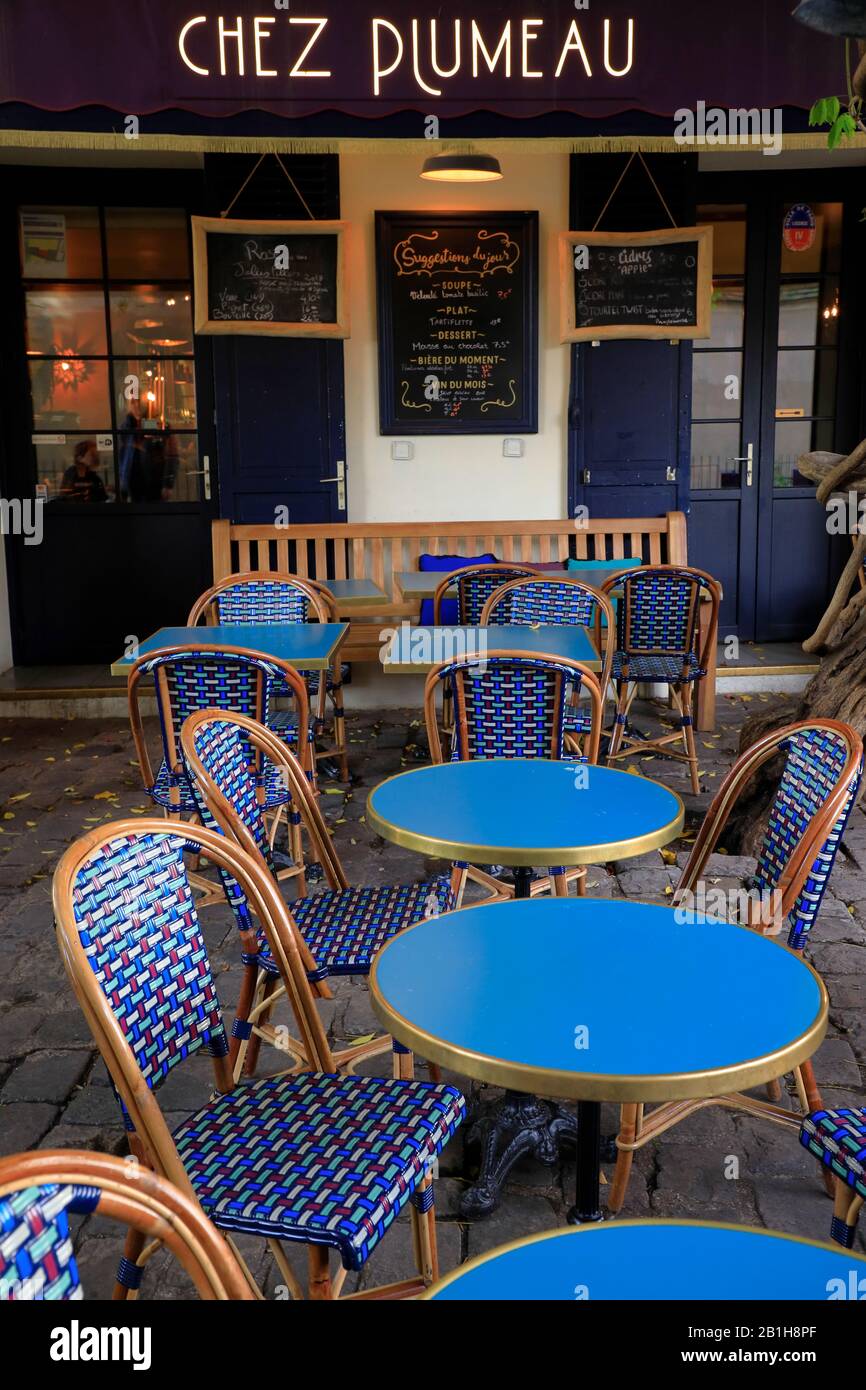 Blue chairs and tables in typical Parisian cafe style in the outdoor seating of Chez Plumeau restaurant.Montmartre.Paris.France Stock Photo
