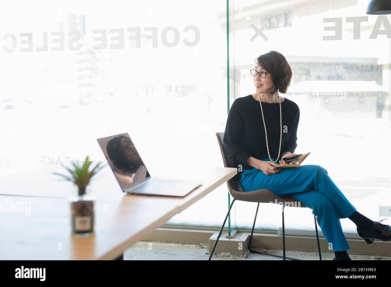 Smiling woman looking over shoulder in coworking office space Stock Photo