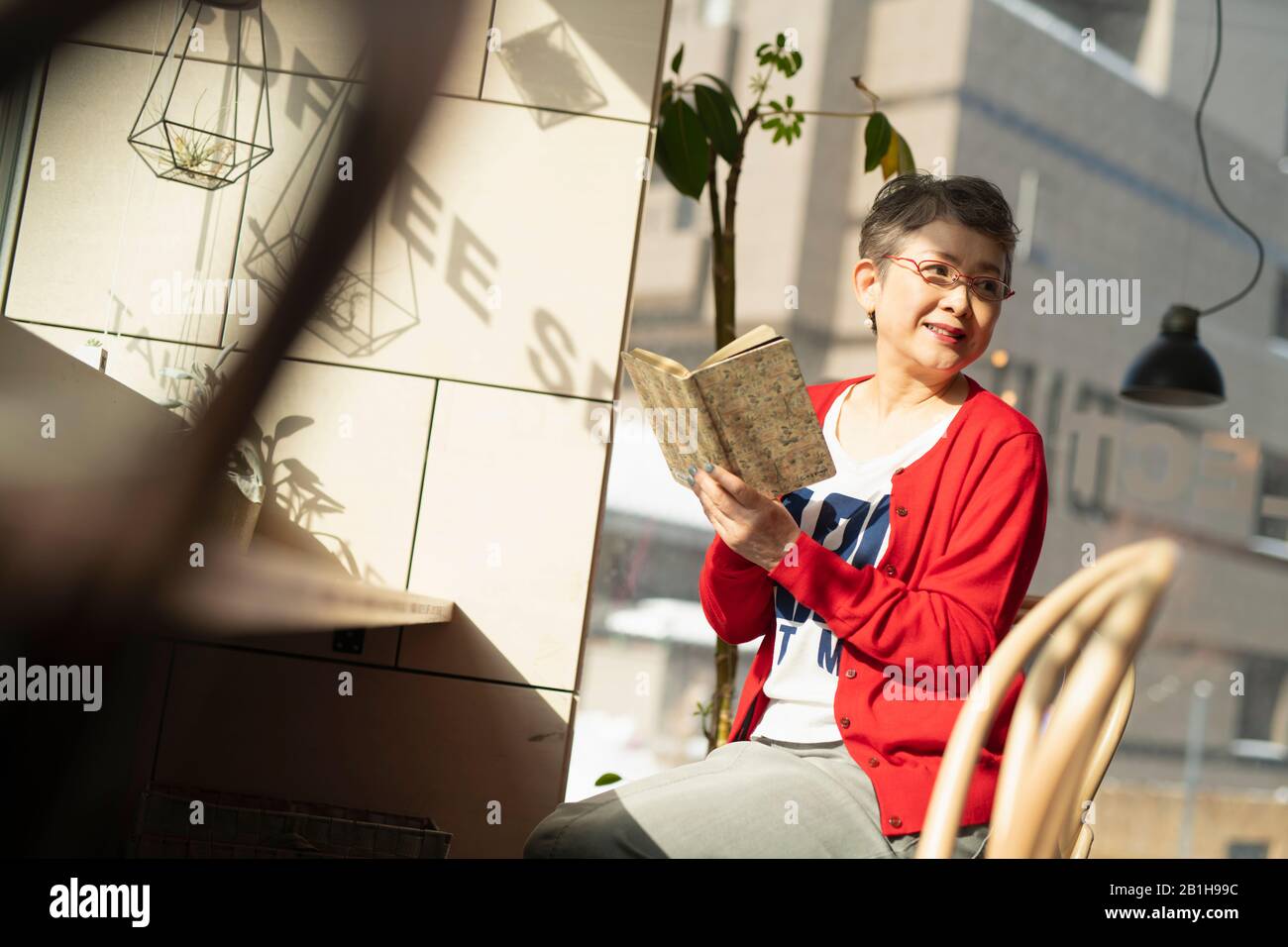 Smiling senior woman looking over shoulder with book Stock Photo