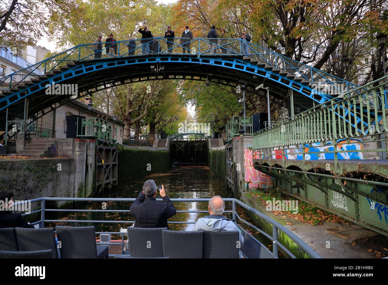 Tour boat under an Iron bridges towards a Lock in Canal Saint Martin