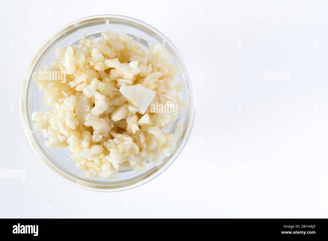 Crushed Garlic in glass bowl. Healthy Food Concept Top View on white