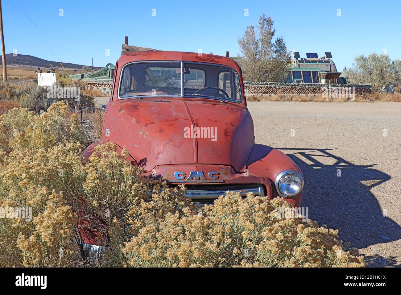 Old car and earthship building with greenhouse and solar panels, part of the Greater World Earthship Community, near Taos, NM Stock Photo