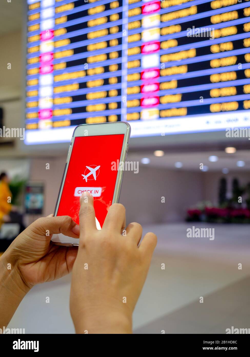 Flight check-in by mobile phone. Hand touching on smartphone screen to check-in for a flight in terminal airport verticals tyle. Stock Photo