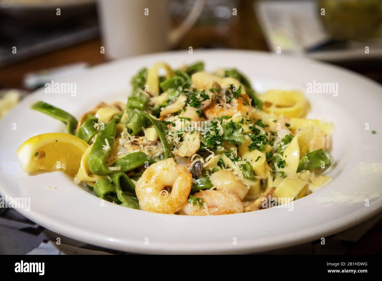 Seafood alfredo in creamy sauce with prawns, scallops and mushrooms sauteed with spinach and egg fettuccine noodles. Stock Photo
