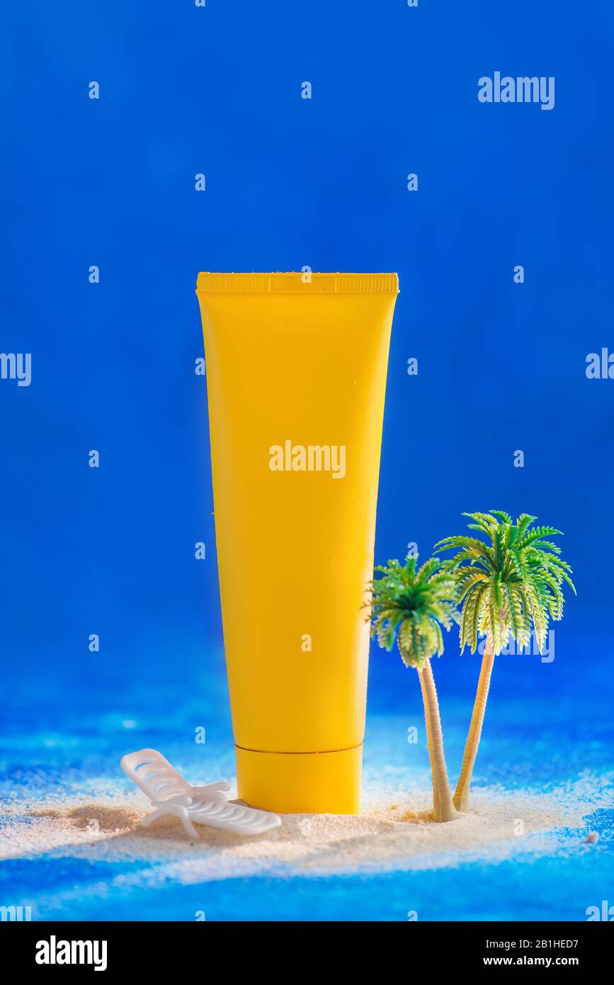 Summer skincare concept with sunscreen tube and miniature palms, blue background with copy space Stock Photo