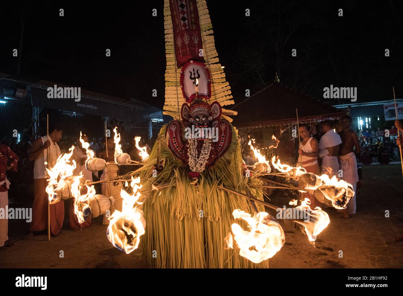 Theyyam performer, surrounded by torches, dances a popular ritual form