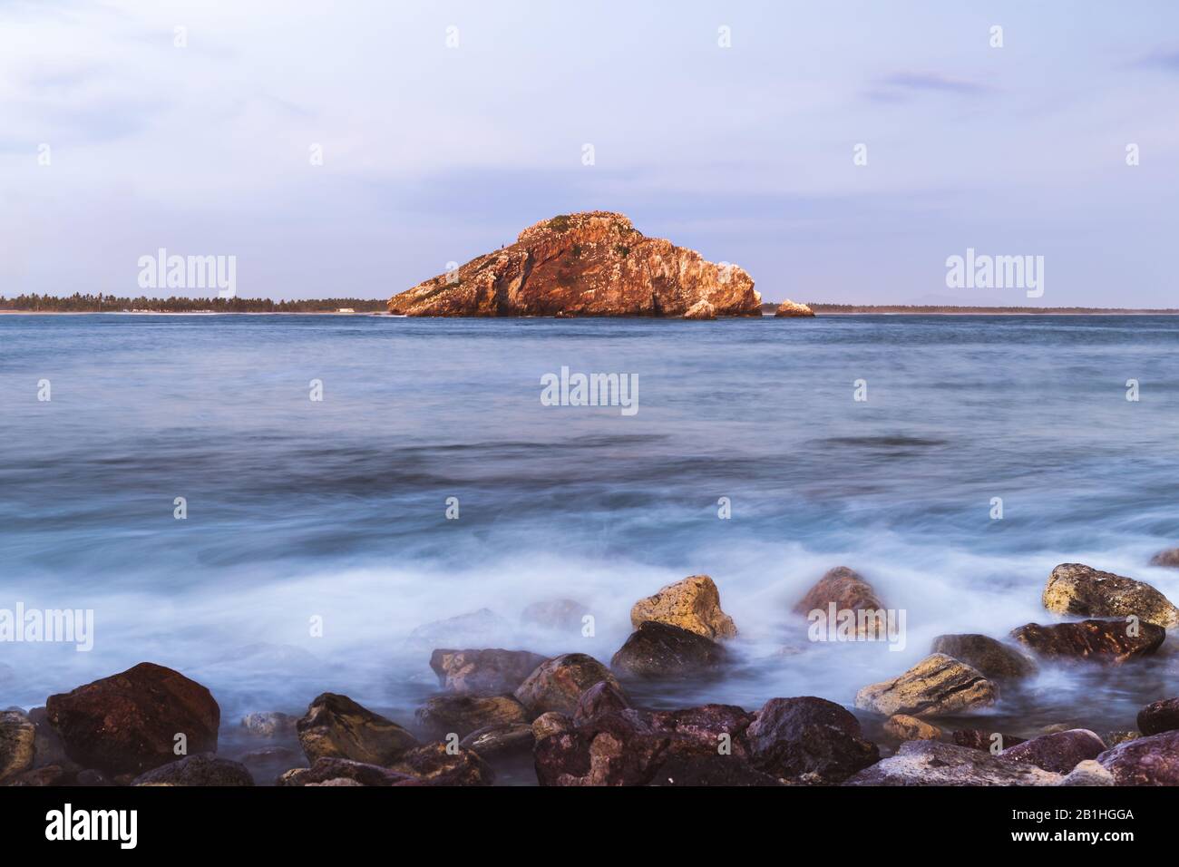 Long exposure photo of the sea, where the waves breaks over the stones in Mazatlan Stock Photo