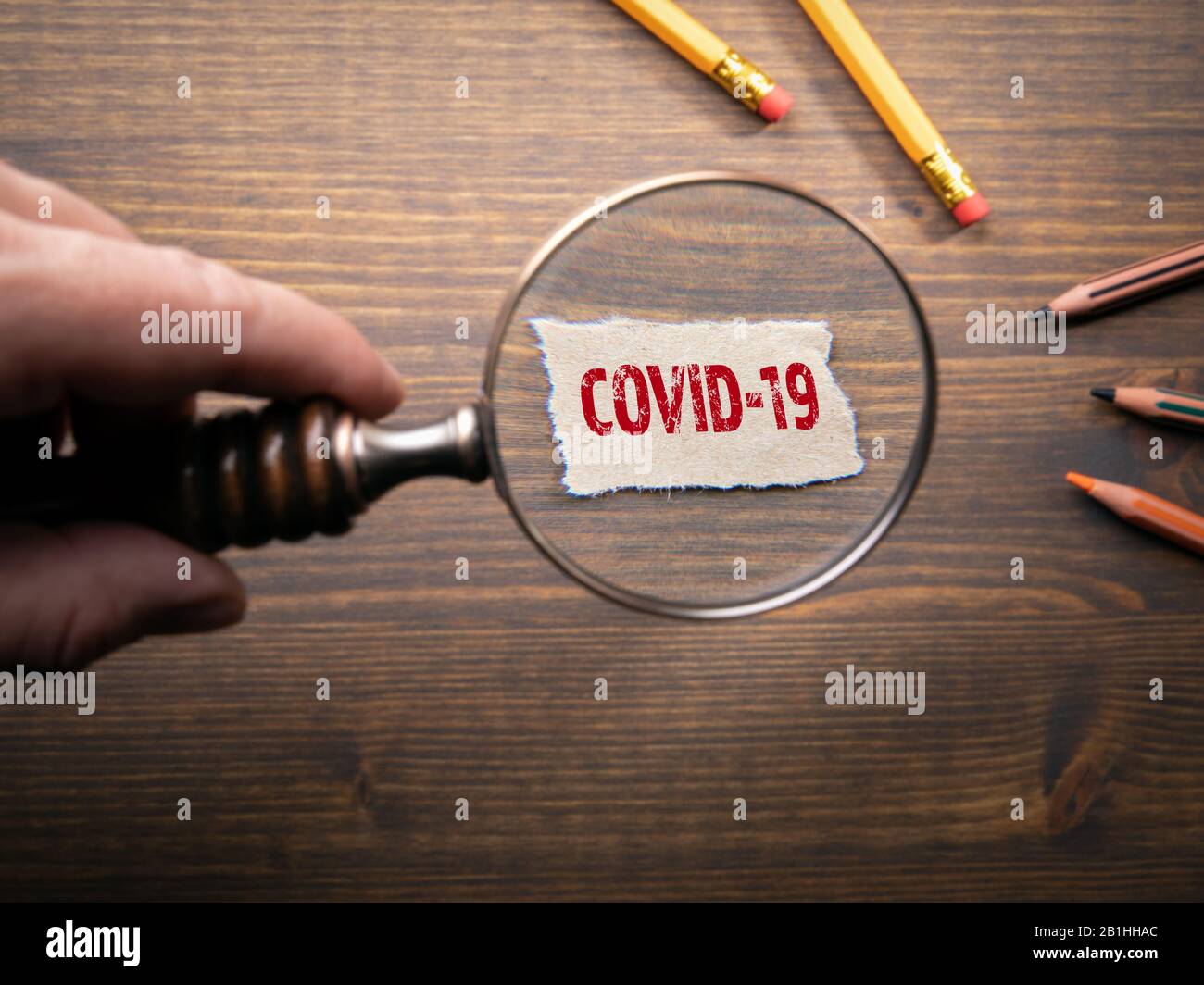 COVID-19. Exploring and explaining coronovirus - outbreak of desease that was first reported from Wuhan, China. Man's hand, holding magnifying glass Stock Photo