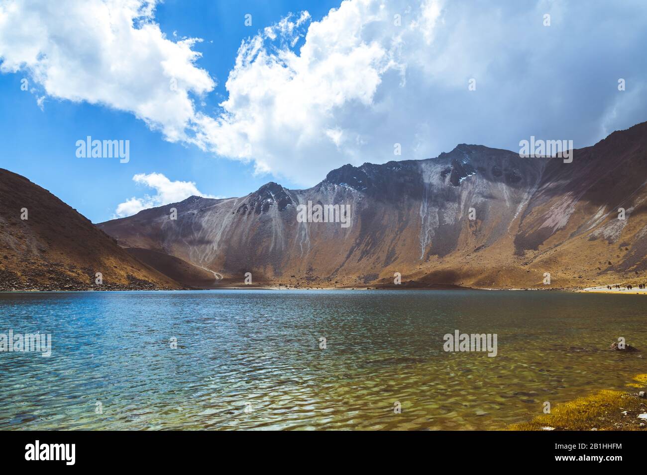 A lake with crystal clear waters, surrounded by snowy mountains and a ...