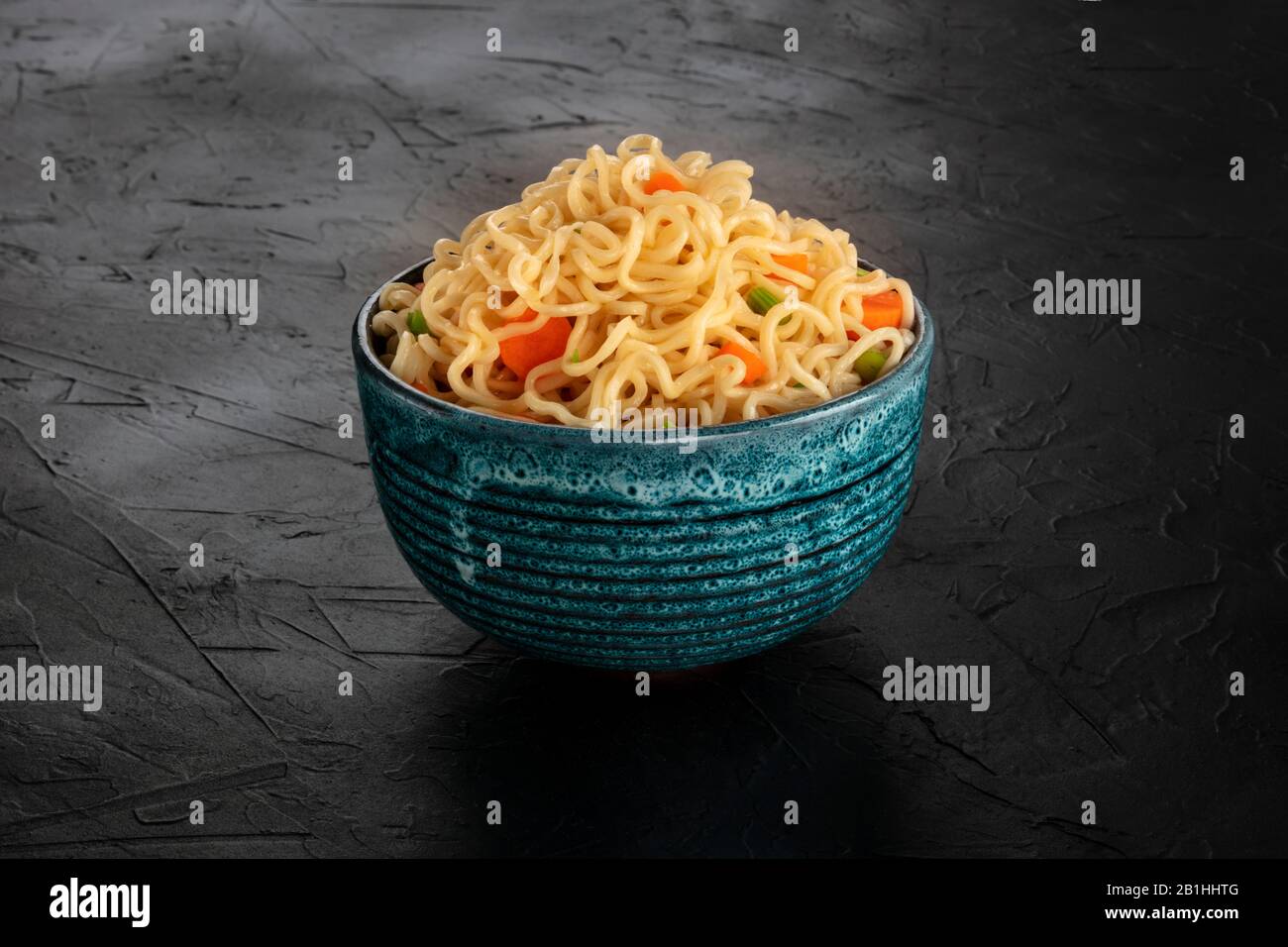 Instant noodles with carrot and scallions, a bowl of soba with vegetables on a black background Stock Photo
