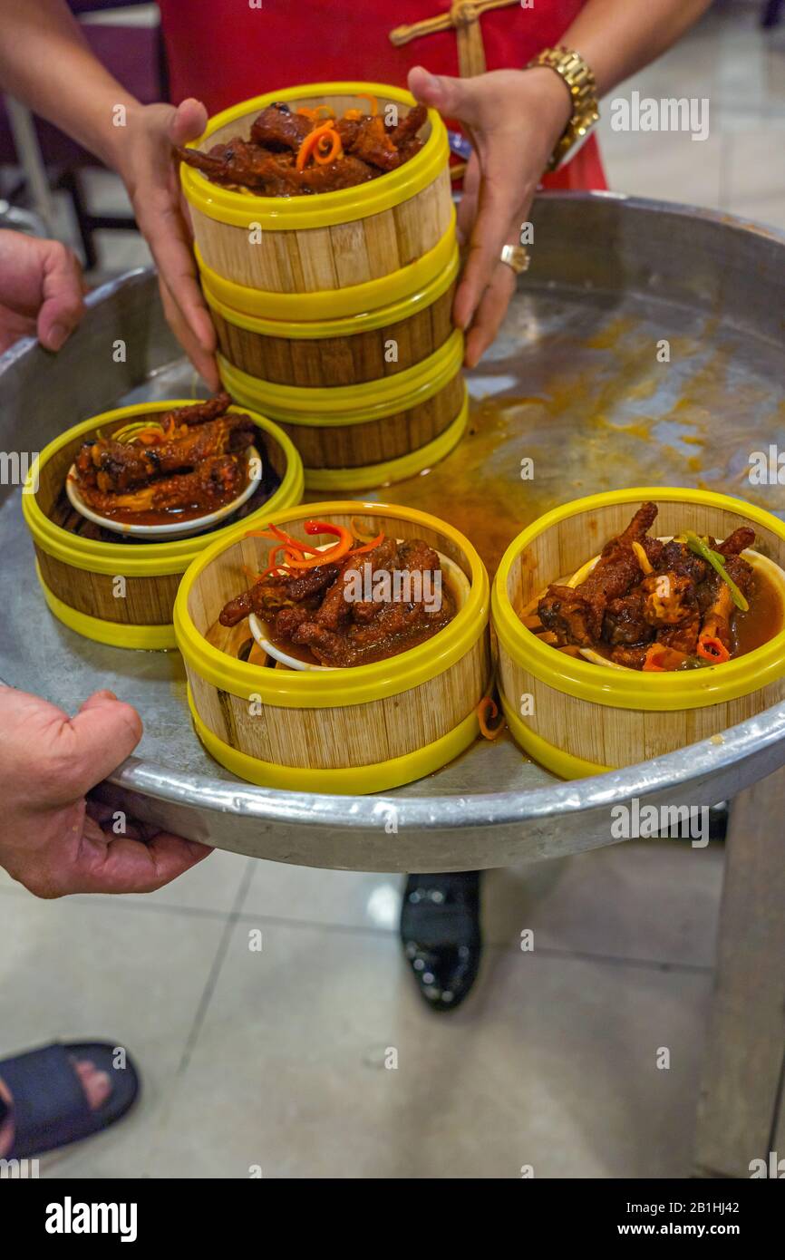 Chinese waitress serving stewed chicken feet in dimsum restaurant Stock