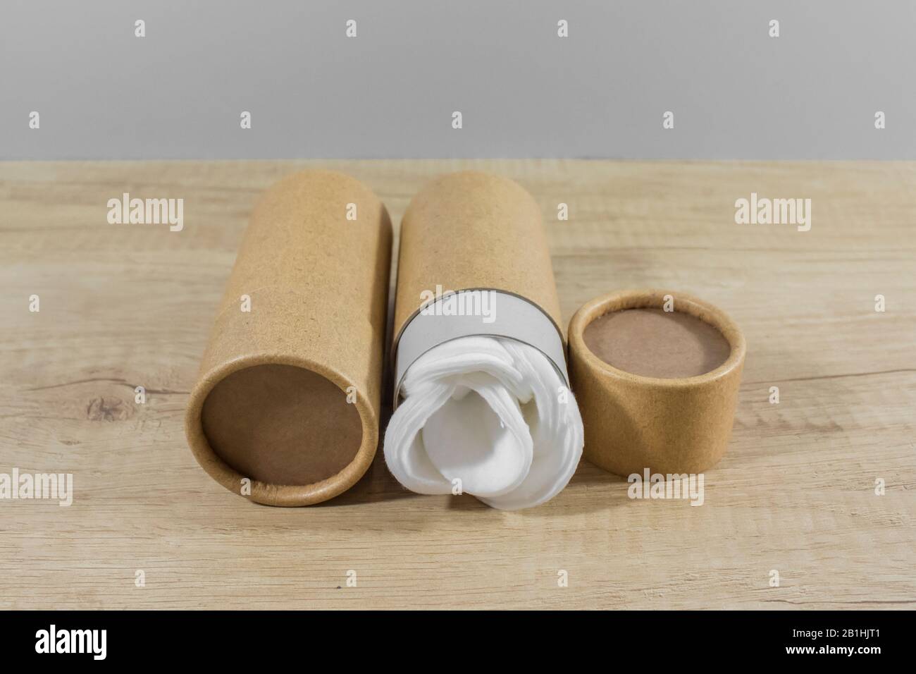 Paper plastic free tubes with white cotton disks inside on wooden table