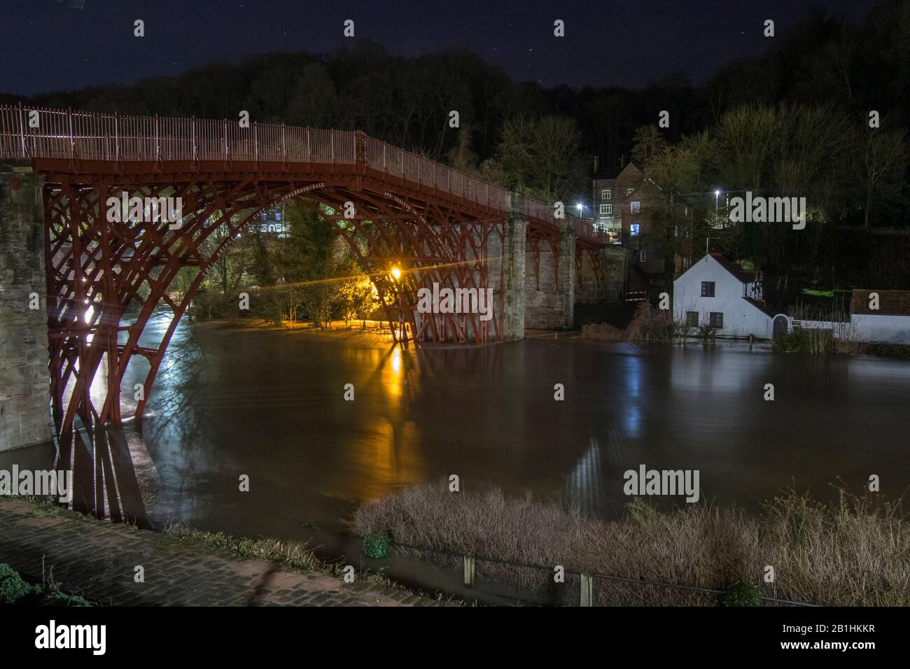 Ironbridge, UK. 26th Feb 2020. 2-3am in the morning, one week on from previous records and Ironbridge is once again experiencing record flood levels. Whilst in the shadow of the famous bridge after which the town is named, flood defences are battling to hold back the rising river levels, the night time long exposure creates a serene millpond image of the historical landmark itself. Credit: Paul Bunch/Alamy Live News Stock Photo