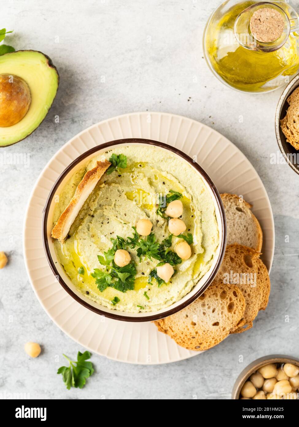 Healthy avocado hummus in ceramic bowl with olive oil, chick peas and