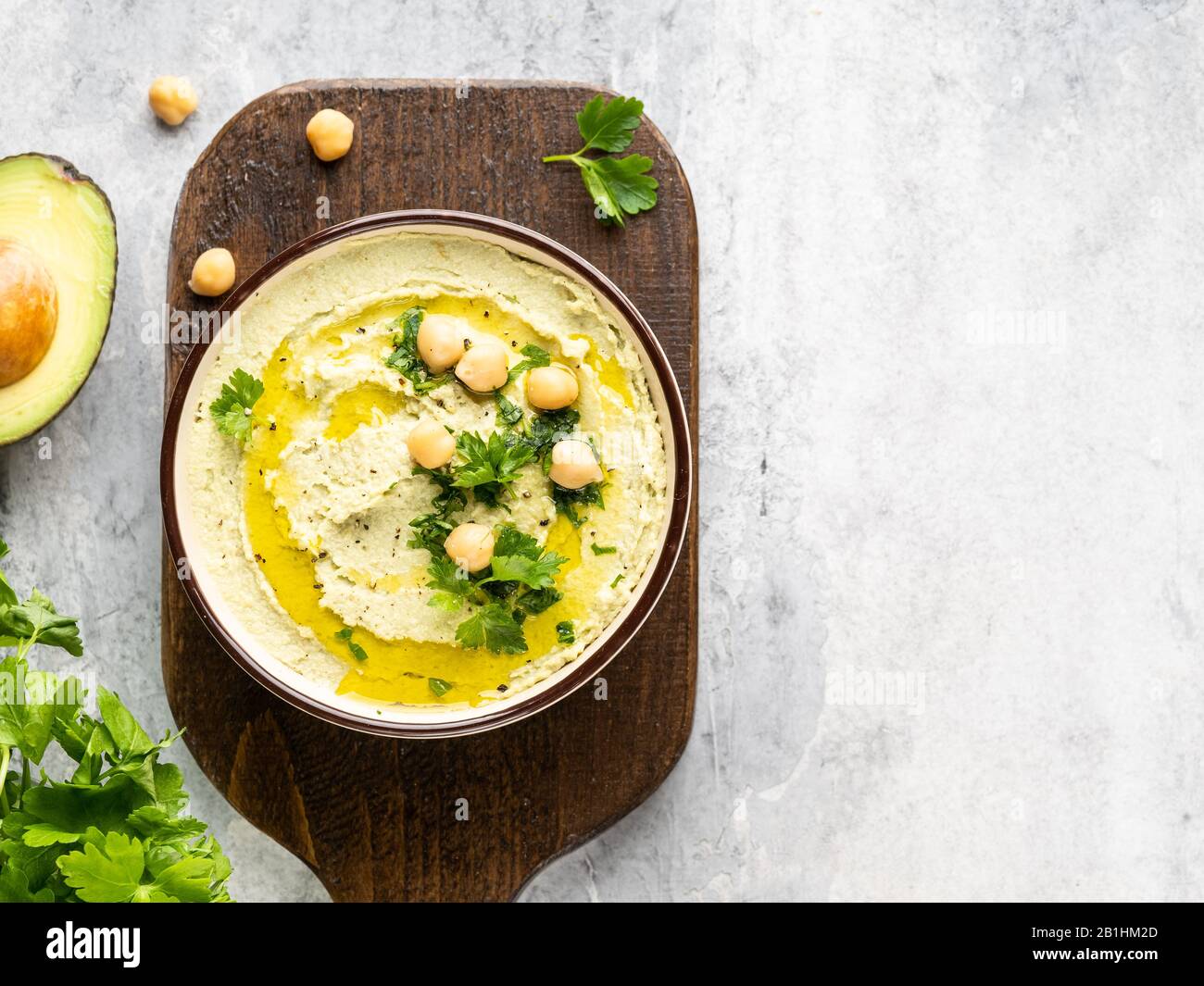 Healthy avocado hummus in ceramic bowl with olive oil, chick peas and