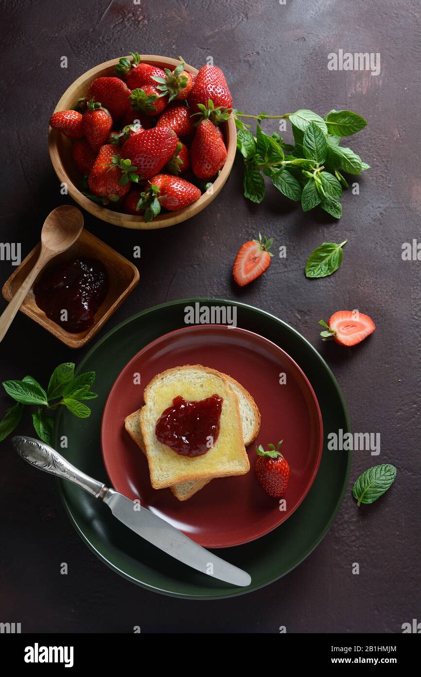 Toasts with strawberry jam for breakfast, rustic style Stock Photo