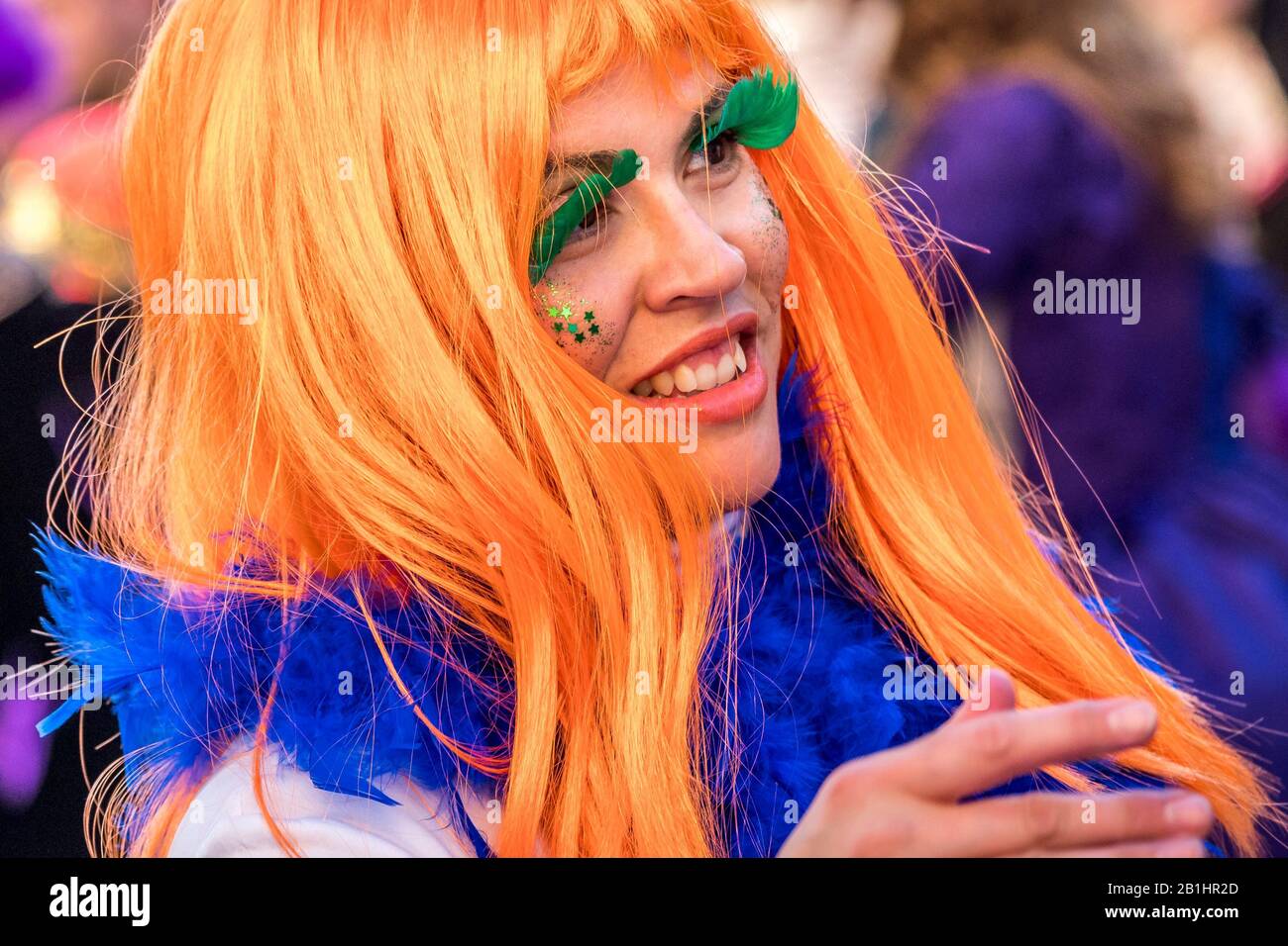 woman with a colorful orange wig and green eyelashes during a street carnival parade  Herencia, Castile-La Mancha, Spain February, 22, 2020 Stock Photo
