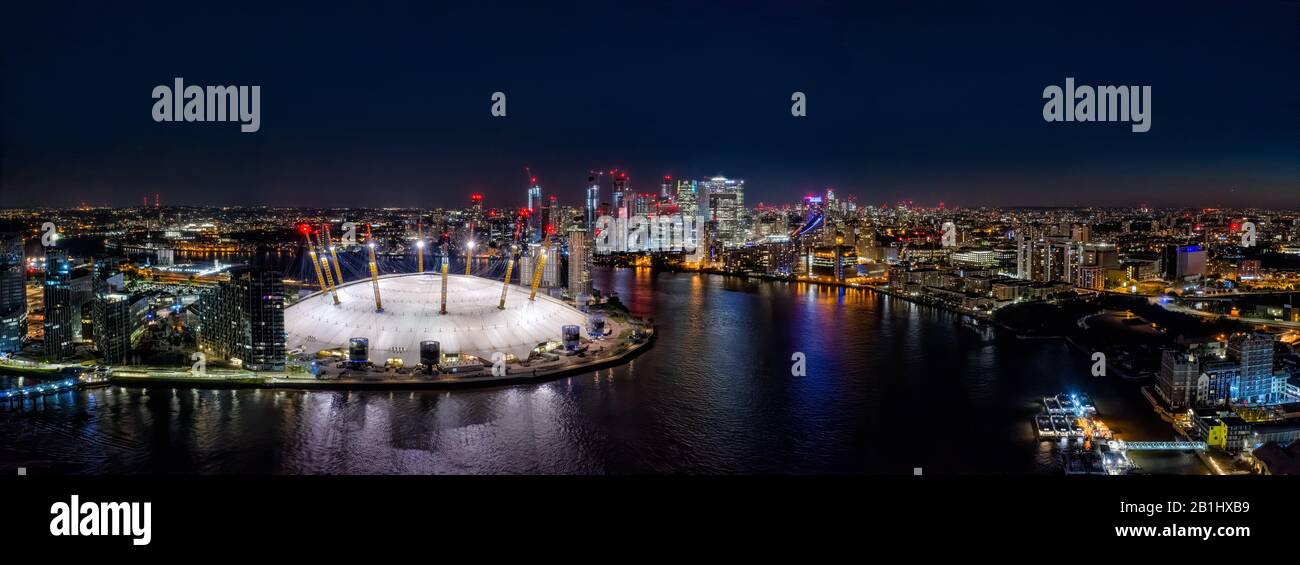 The O2 Arena and Canary Wharf from above the River Thames, london at night with Canary Wharf in the background illuminated at night. Aerial drone view Stock Photo