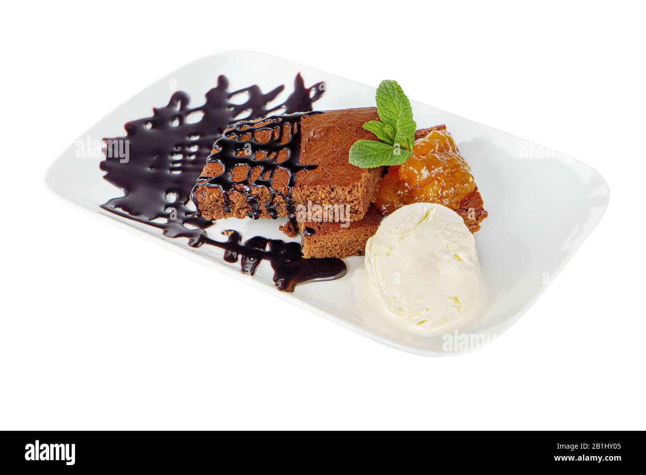 chocolate cake brownie on a white plate apricot, peach jam, mint, topping and vanilla ice cream isolated on white background. Dessert for a menu in a Stock Photo