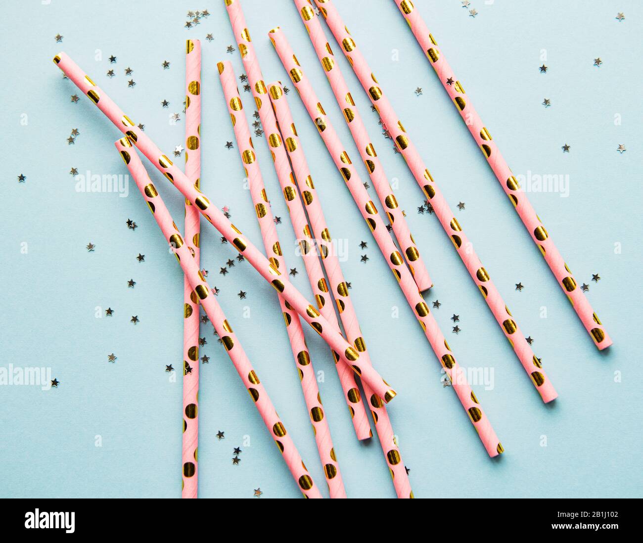Drinking straws for party and confetti on blue background with copy space. Top view of colorful paper disposable eco-friendly straws for summer cockta Stock Photo
