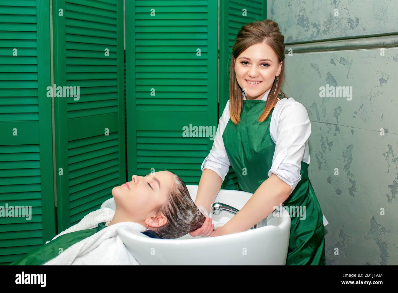 Hairdresser washing woman's hair in sink in beauty salon Stock Photo