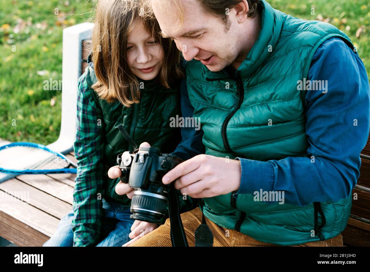 A father and son of school age with photo camera sitting on bench Stock Photo