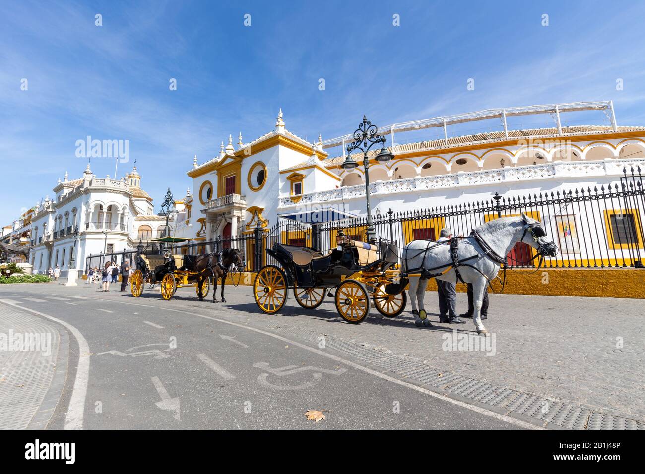 Horse-drawn carriages waiting in front of the entrance to the Bullfighting arena of Seville, Andalucia, Spain. Stock Photo