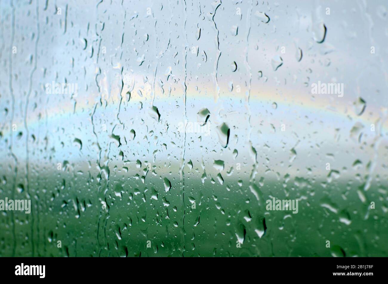 If you keep your focal point to close to your nose you won't see the endless possibilities ahead. Raindrops on window, rainbow in the distance. Stock Photo
