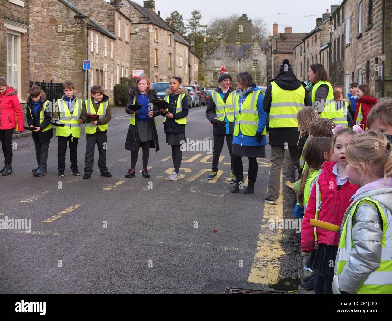 School children ready with frying pans and pancakes at starting line at Winster Pancake Races Shrove Tuesday Pancake Day Derbyshire UK Stock Photo