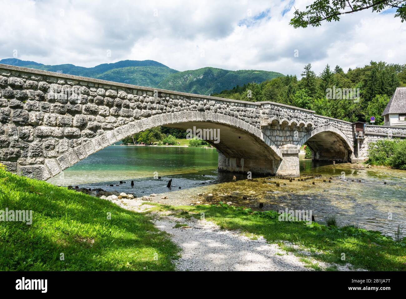 Bridge spanning Sava Bohinjka river in Slovenia at the point where it reaches Lake Bohinj in Ribcev Laz, in summer. Stock Photo