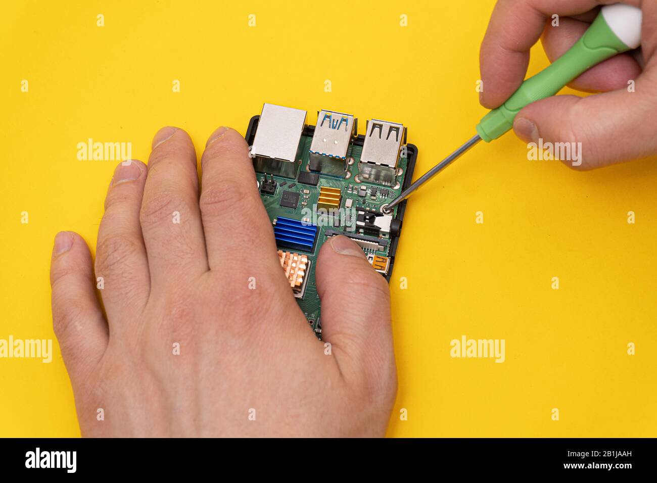 Man fixes microcomputer with screwdriver Stock Photo
