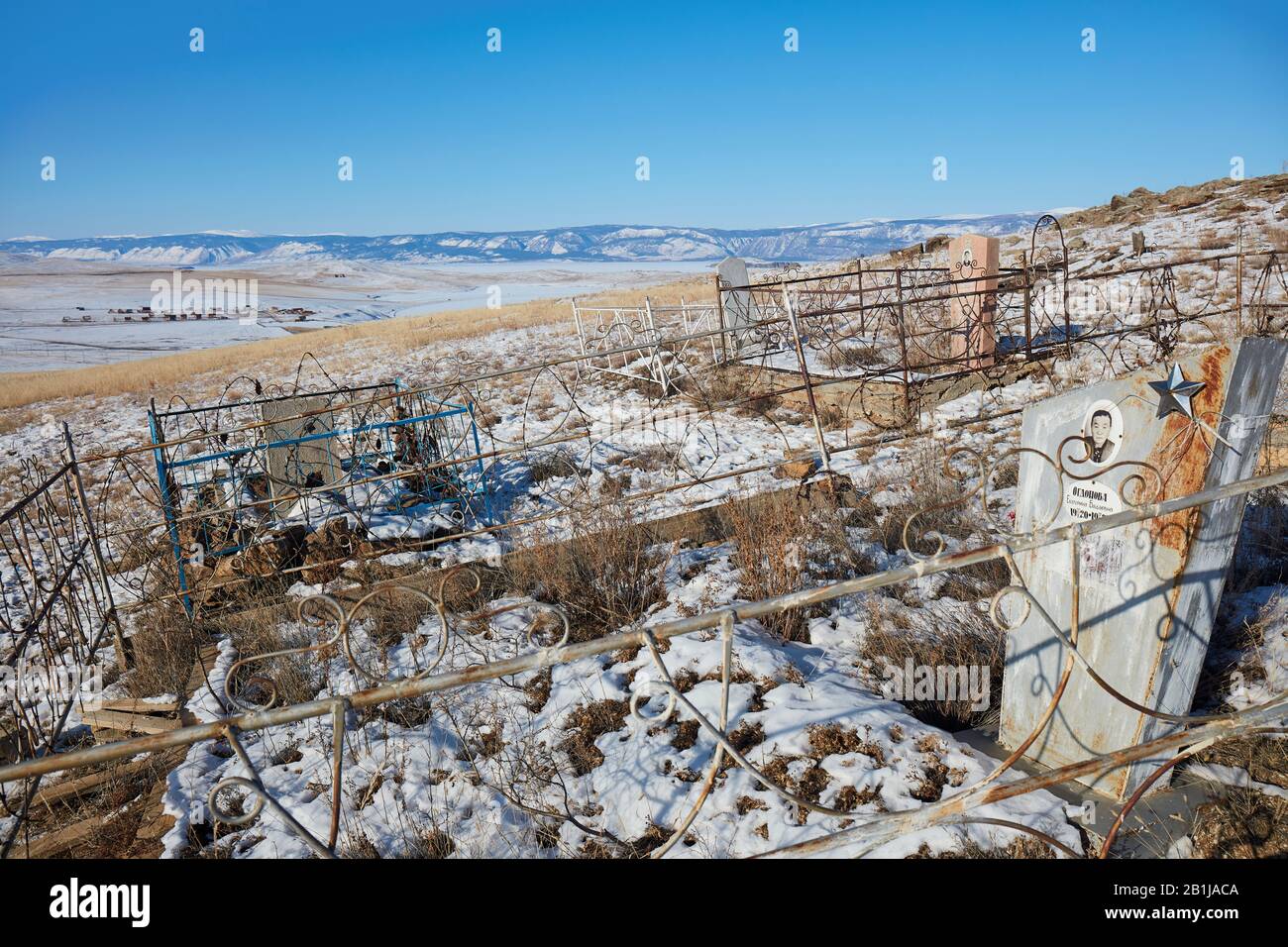 Cemetery with village in the distance in Siberia Stock Photo