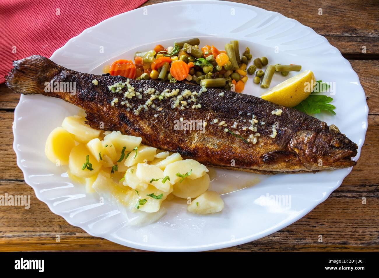 Plate of Bohinj trout with boiled potatoes and salad in Slovenia. Stock Photo