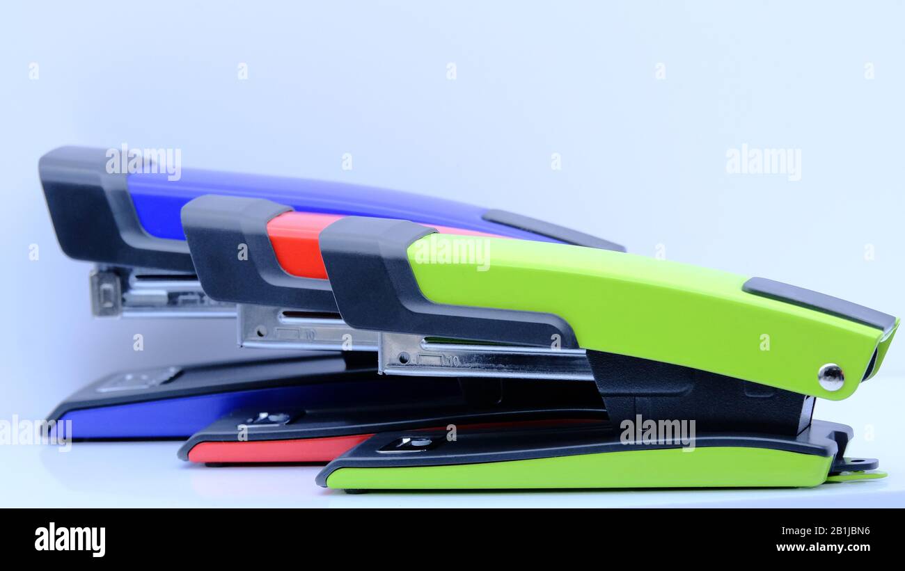 Three green, red and blue staplers standing next to each other on a white background Stock Photo