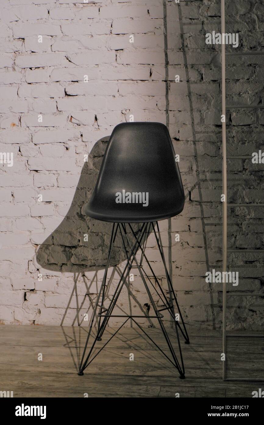 Black bar stool on a metal platoon carcass against a white brick wall