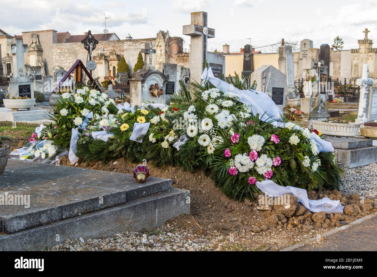 Fresh grave tomb with funeral wreaths and flowers in cemetery, Sopron, Hungary Stock Photo