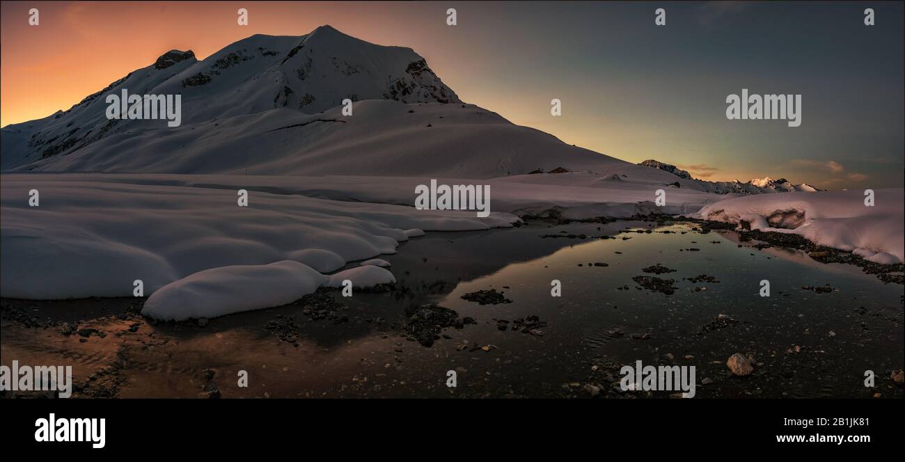Panorama photo of the slow flowing Engstligen brook in snowscape of the Engstligenalp  at dusk Stock Photo