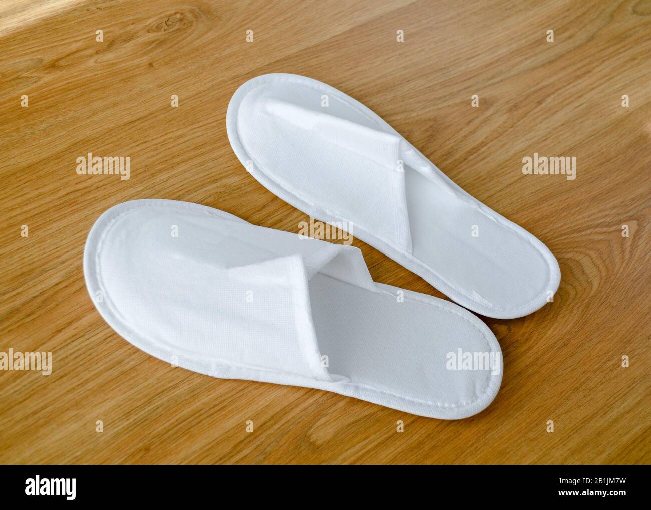 Couple new ecofriendly fabric disposable slippers lie on wooden floor