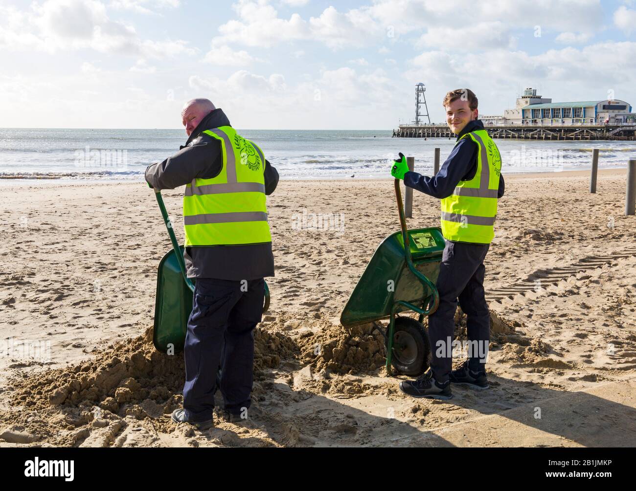 Bournemouth, Dorset, UK. 26th Feb 2020. Councillor Lewis Allison (on the right), gets stuck in and gives the seafront rangers (Terry, left) a hand to clear the sand from the promenade, blown up from the recent strong winds and Storm Dennis.   Councillor Allison is Labour Councillor for Boscombe West and Portfolio Holder, Cabinet Member, for Tourism, Leisure and Communities at BCP (Bournemouth, Christchurch and Poole) Council.  Credit: Carolyn Jenkins/Alamy Live News Stock Photo