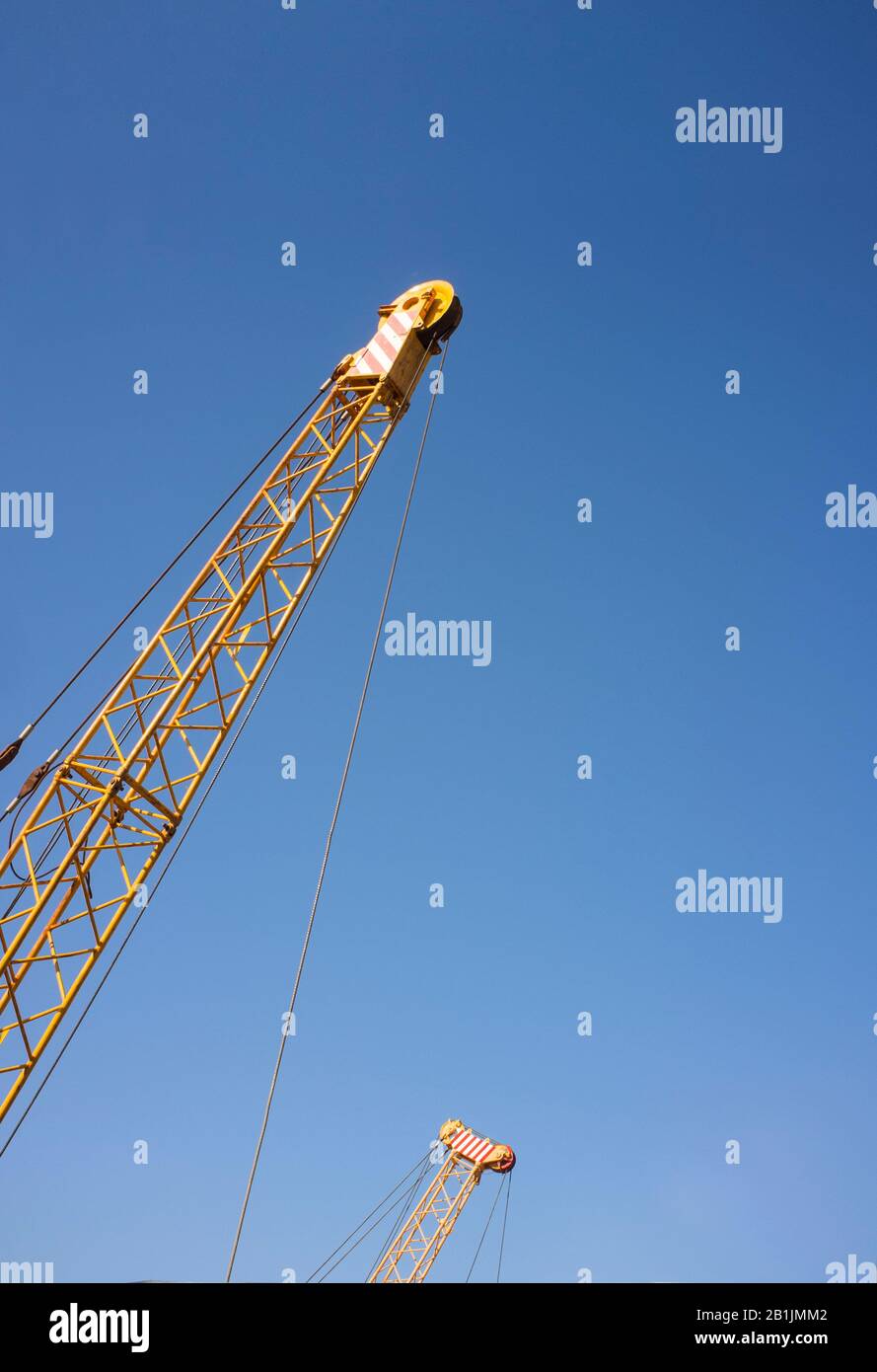 Cranes top pulley over blue sky. Construction background Stock Photo