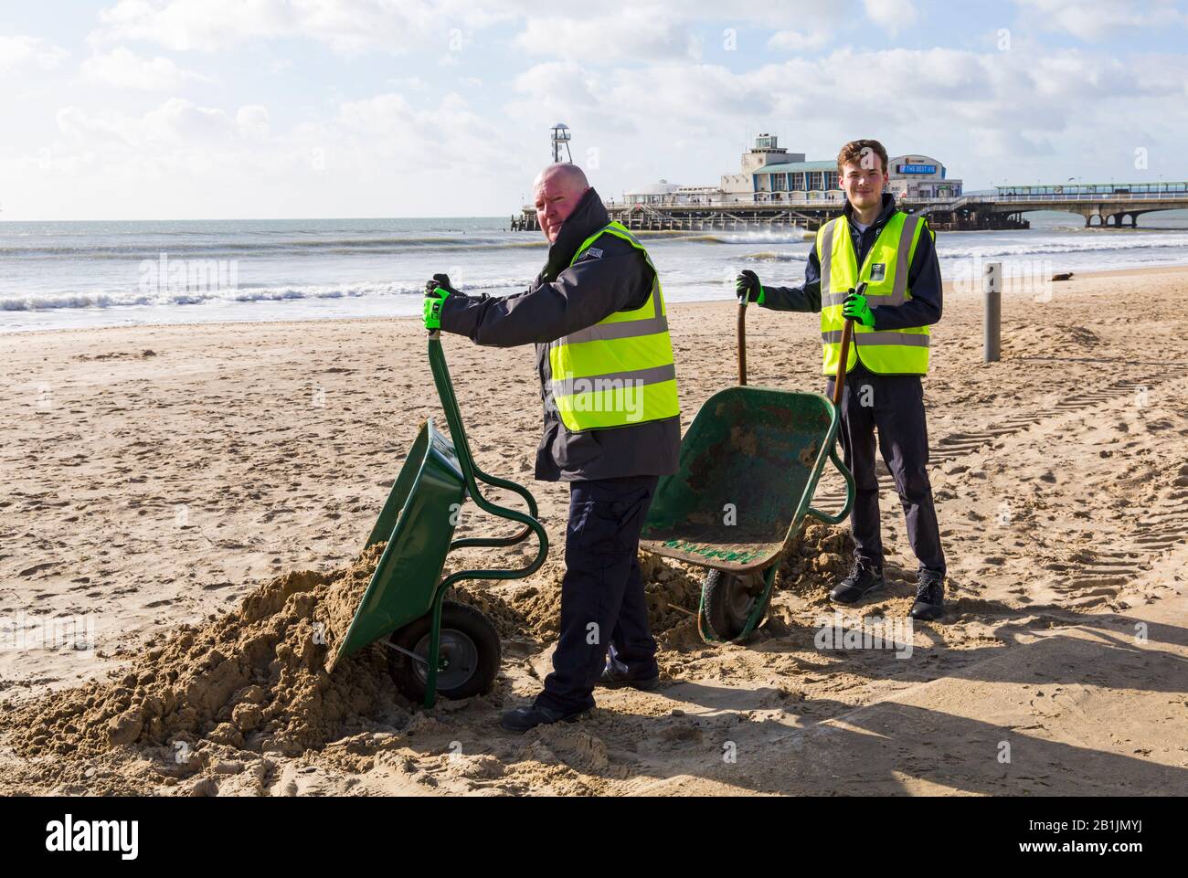 Bournemouth, Dorset, UK. 26th Feb 2020. Councillor Lewis Allison (right), gets stuck in and gives the seafront rangers (Terry, left) a hand to clear the sand from the promenade, blown up from the recent strong winds and Storm Dennis.   Councillor Allison is Labour Councillor for Boscombe West and Portfolio Holder, Cabinet Member, for Tourism, Leisure and Communities at BCP (Bournemouth, Christchurch and Poole) Council.  Credit: Carolyn Jenkins/Alamy Live News Stock Photo